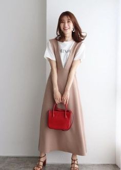 Woman in a beige midi dress over a white t-shirt, holding a red handbag