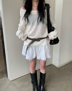 Woman in a white off-shoulder top and mini skirt with black boots and bag