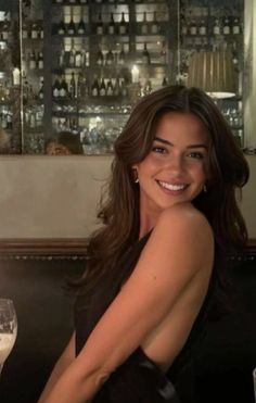 Woman with long dark hair in a black dress smiling in a restaurant
