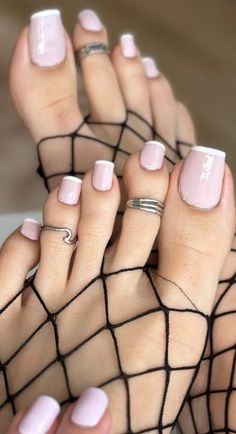Feet with pink and white pedicure, wearing fishnet stockings and toe rings