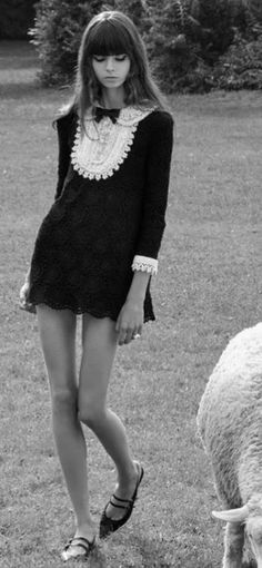 Woman in a black dress with a white lace collar standing outdoors
