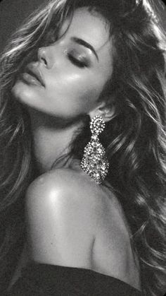 Woman with long wavy hair and a large earring in a black and white portrait