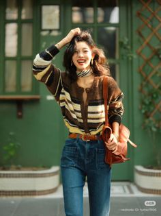 Woman in a striped cardigan and blue jeans smiling outdoors