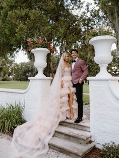 A couple in wedding attire standing on outdoor stairs