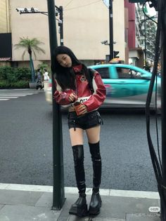 Woman in a red jacket, black shorts, and thigh-high boots on a street