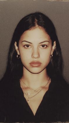 Woman with long dark hair and layered necklaces in a portrait shot