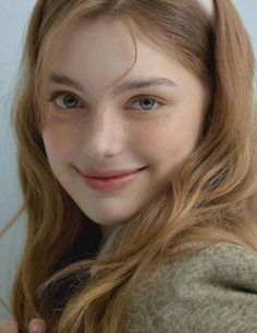Young woman with long wavy hair and freckles smiling at the camera