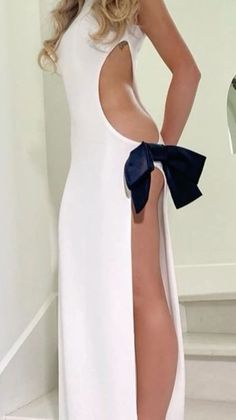 Woman in a white dress with a large side cut-out and black bow