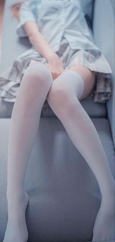 Person in a school uniform and white thigh highs sitting indoors