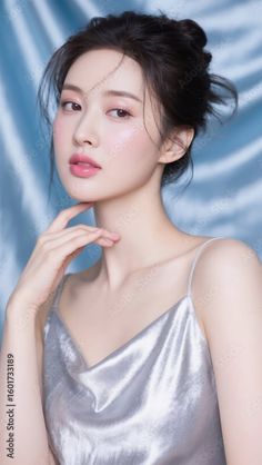 Woman with an updo wearing a silver top against a blue background