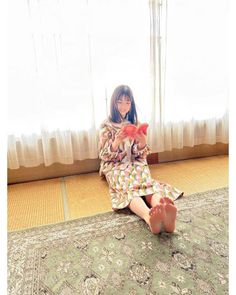 Woman in a colorful patterned dress sitting on a tatami mat and reading a book