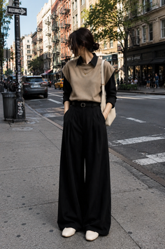 Woman in wide leg pants and a sleeveless top standing on a city street
