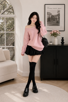 Woman in a pink off-shoulder sweater and black lace skirt with thigh-high socks