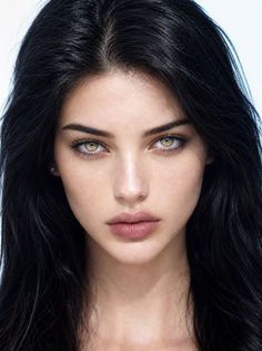 Close-up portrait of a woman with long black hair and green eyes