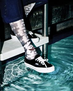 Person wearing black sneakers and patterned socks with an anklet in a swimming pool