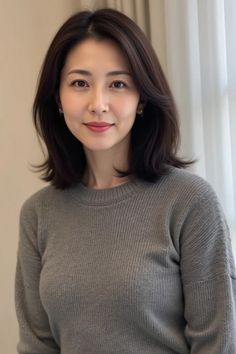 Woman with short dark hair wearing a gray sweater indoors