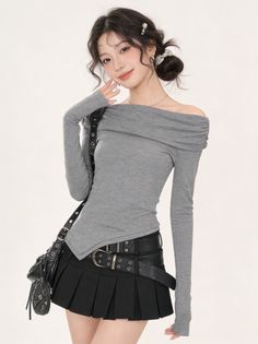 Woman in a gray off-shoulder top and black pleated skirt with multiple belts