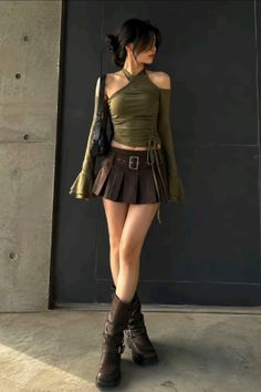 Woman in a green halter top, brown pleated skirt, and knee-high boots