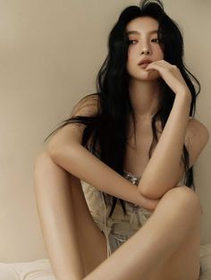 Woman with long black hair in a light top, sitting with exposed skin