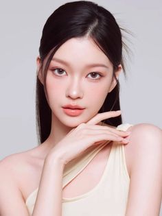 Woman with long dark hair wearing a light-colored one-shoulder top