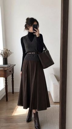 Woman in a black turtleneck and brown midi skirt taking a mirror selfie