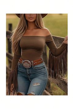 Woman in an off-shoulder top with fringe sleeves, distressed jeans, and a cowboy hat