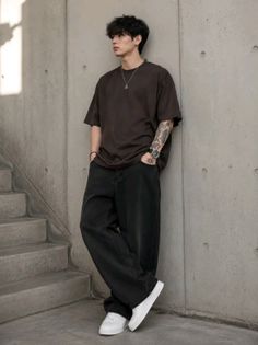 Man with short hair and tattoos wearing an oversized t-shirt and baggy jeans