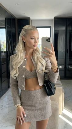 Woman in a tweed jacket and mini skirt taking a mirror selfie