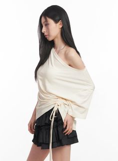 Woman with long black hair wearing an off-shoulder top and black skirt