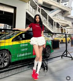 Woman in a red top and white ruffled skirt standing next to a taxi