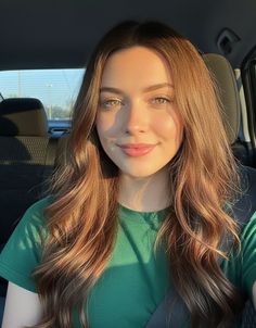 Woman with long hair and green eyes in a car during golden hour