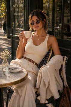 Woman in sunglasses and a white tank top sitting at an outdoor cafe