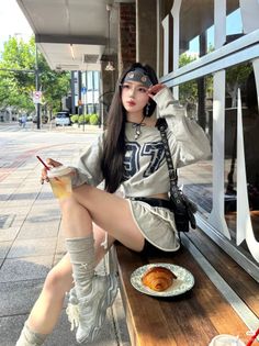 Woman in a cropped sweatshirt and mini skirt sitting on a bench outdoors