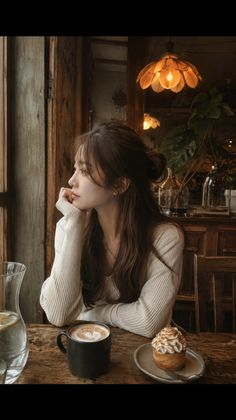 Woman with long hair sitting at a cafe table with coffee and dessert