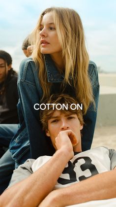 Woman with long blonde hair in a denim jacket with a man resting on her lap