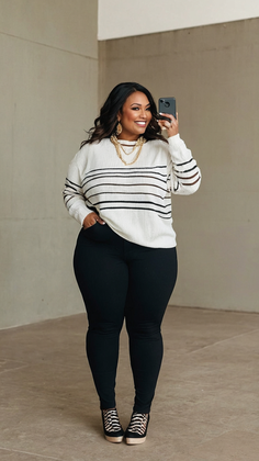 Woman with long hair wearing a striped sweater and black pants, smiling and holding a phone