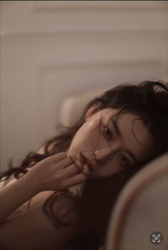 Woman with long dark hair in soft, warm lighting, with exposed skin