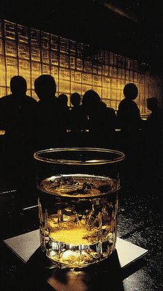 Glass of whiskey on a bar with blurred silhouettes in the background