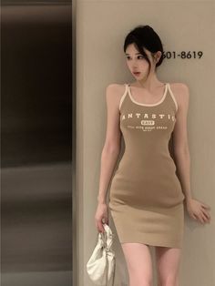 Woman in a short bodycon dress holding a small white bag indoors