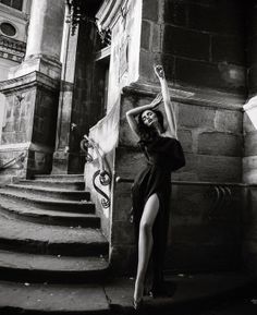 Woman in a long black dress with a high slit posing outdoors