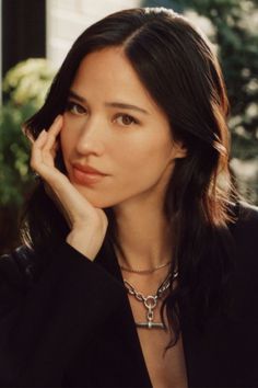 Woman with long dark hair wearing a black jacket and silver necklace