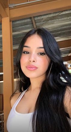Woman with long black hair and a lip piercing wearing a white top