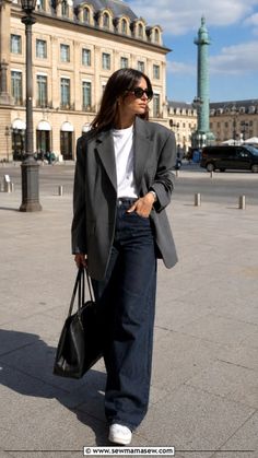 Woman in a blazer and wide-leg jeans walking in a city square