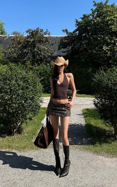 Woman in a cowboy hat, halter top, and mini skirt outdoors