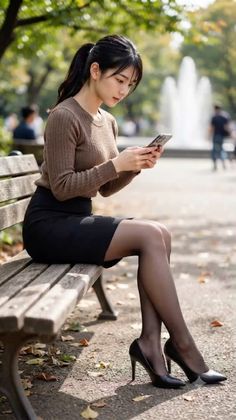 Woman with a ponytail sitting on a park bench, looking at her phone