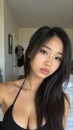 Woman with long black hair wearing a black top indoors