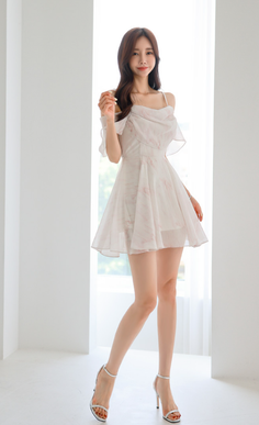 Woman in a white mini dress and high heels posing indoors