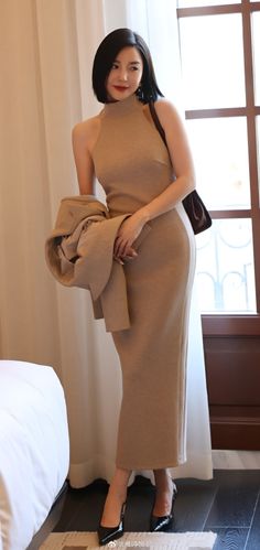 Woman in a beige dress and black heels standing indoors