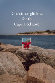 Gift box with a red ribbon on a rocky shore with the ocean in the background