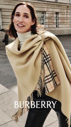 Woman in a beige shawl and black pants on a city street